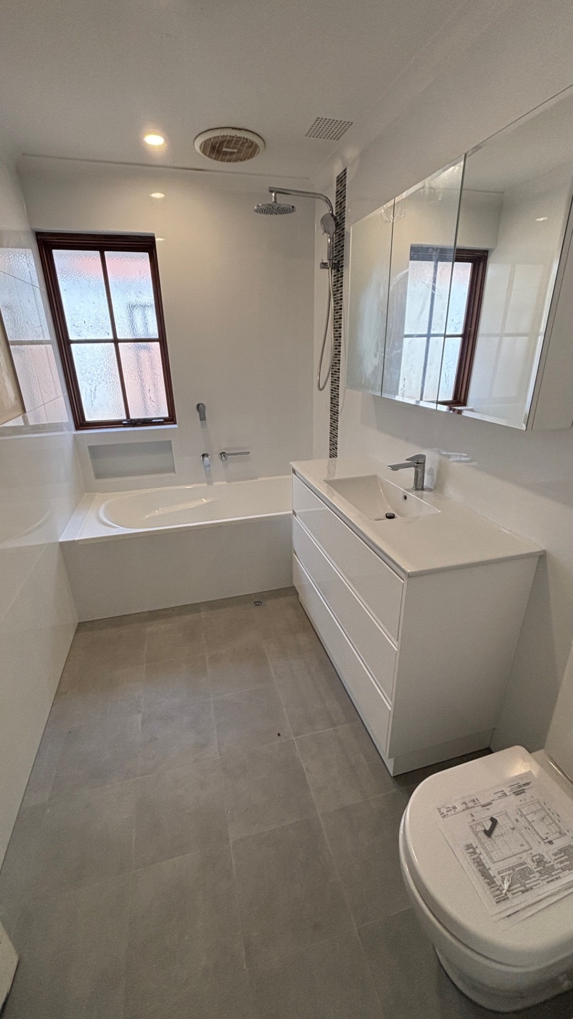 Finished bathroom renovation with freestanding vanity and rain shower
